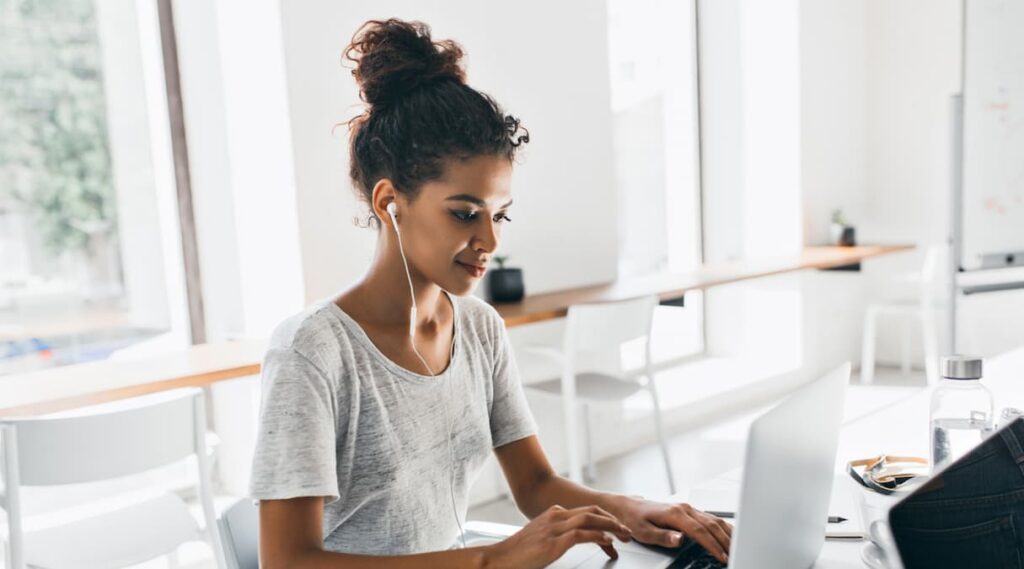 Mulher lojista sentada em sua mesa de trabalho e aprendendo a como usar o frete em uma campanha de marketing